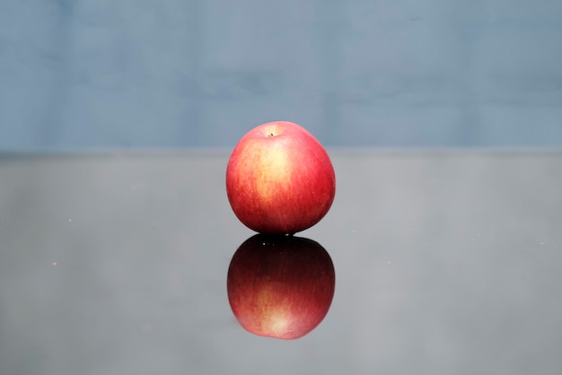 Fresh red apple with reflection on a glass table.