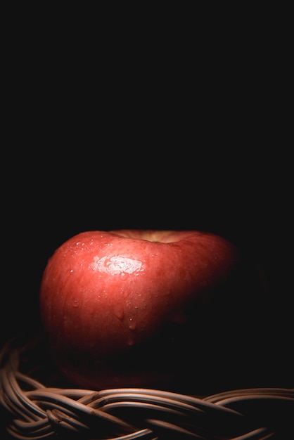 Fresh red apples in the basket On a black background with water droplets lights are falling with space for text