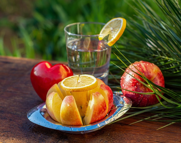 Свежие красные яблоки и стакан воды на деревянном столе