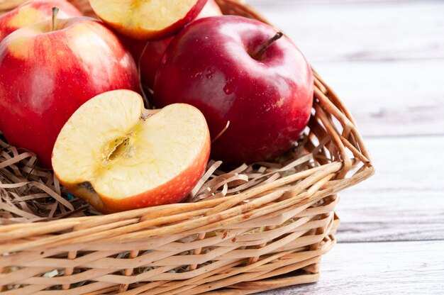 Fresh red apples in a wicker basket Apples closeup with a cut slice Wicker old basket with apples closeup Selective focus