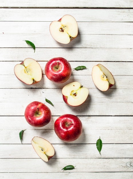 Photo fresh red apples with leaves on white wooden table.