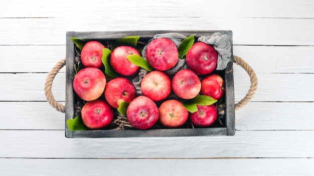 Fresh red apples in a wooden box Organic food On a white wooden background Top view Free space for text