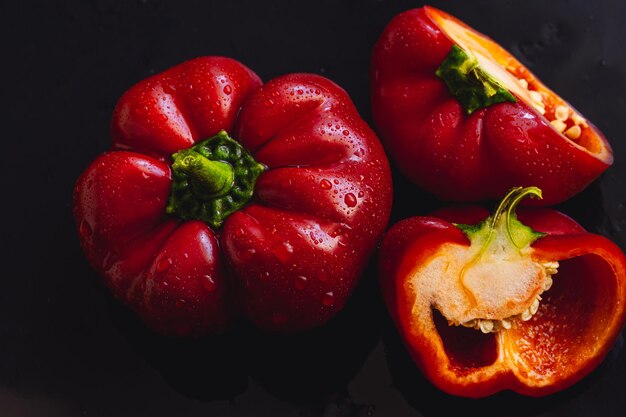 Fresh red bell pepper on black background Top view Tropical abstract background Cloe up Pepper vegetaibles with drops of water