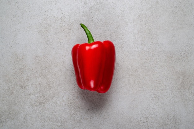 Fresh red bell pepper with drops of water on a gray stone. Background illustration for recipes.