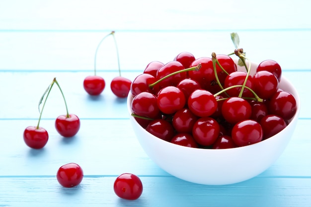 Fresh red cherry fruit in plate on blue wooden table