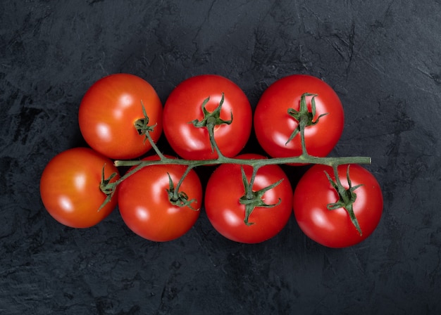 Fresh, red cherry tomatoes on a black textured background. Close-up. Top view