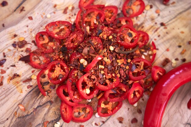 Fresh red chili peppers round slices on wooden cutting board at domestic kitchen