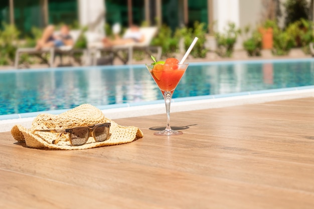 Foto cocktail rosso fresco con ghiaccio in cappello da spiaggia di vetro e