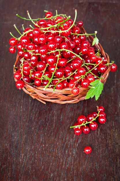 Fresh red currant berries in a wicker bowl in the old wooden table