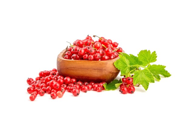 Fresh red currant berries in wooden bowl with green leaves isolated