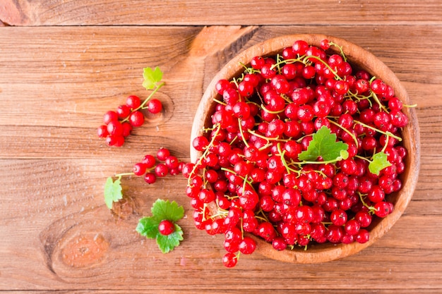 Fresh red currant in a wooden plate on a table