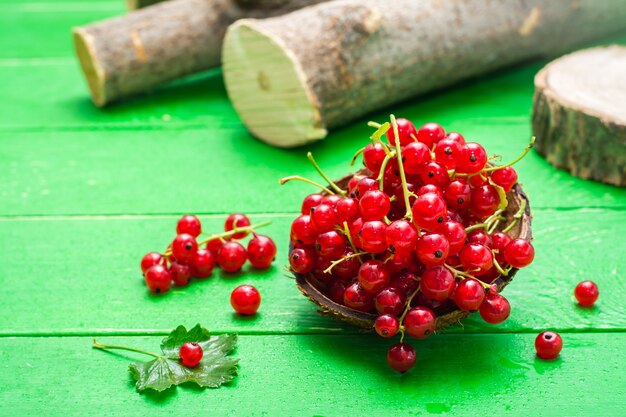 Fresh red currants in a bowl on a green wooden table