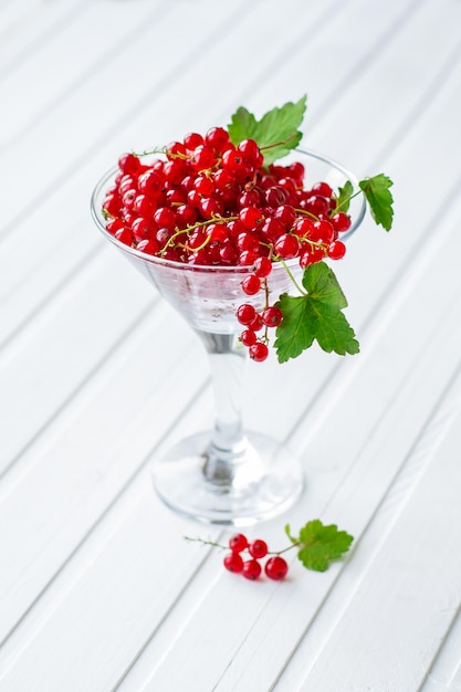 Fresh red currants in a glass beaker on a kitchen wooden table