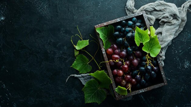 Fresh red grapes with leaves on a black stone table Top view Free space for your text