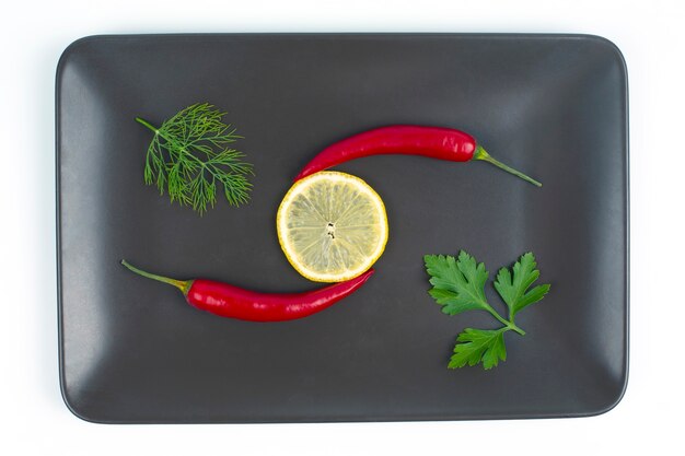 Fresh red hot peppers and lemon on a plate