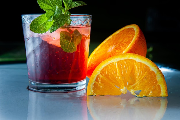 Fresh red lemonade drink with mint orange and ice in glass jar on the dark background Summer cold drink and cocktail