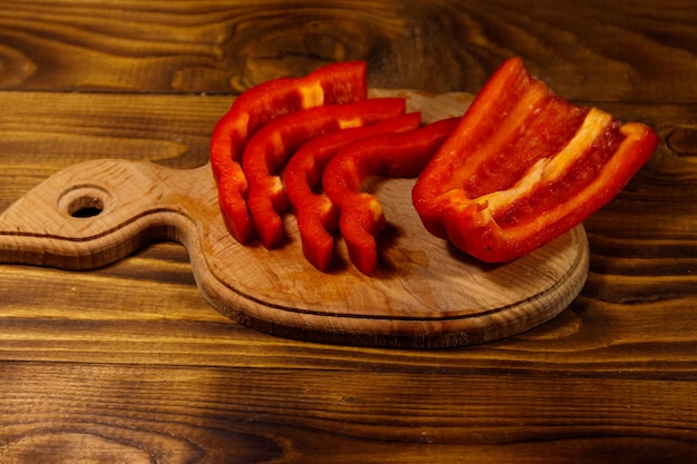 Fresh red pepper on cutting board on wooden table