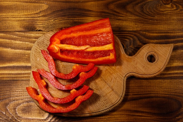 Fresh red pepper on cutting board on wooden table