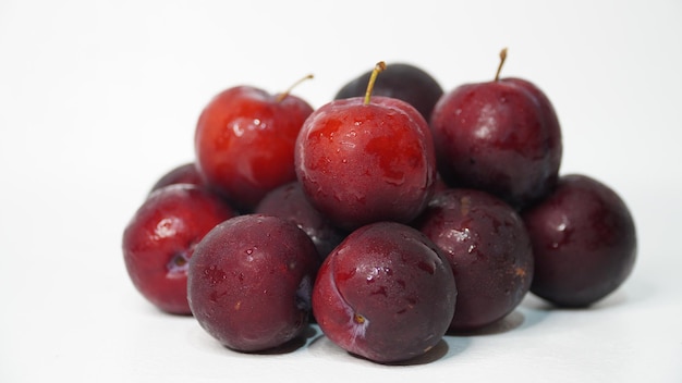 Fresh red plums on a white background