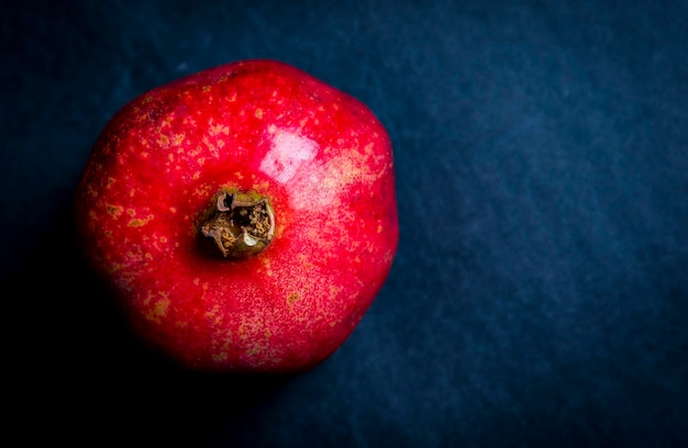 Fresh red pomegranate over dark background studio shot