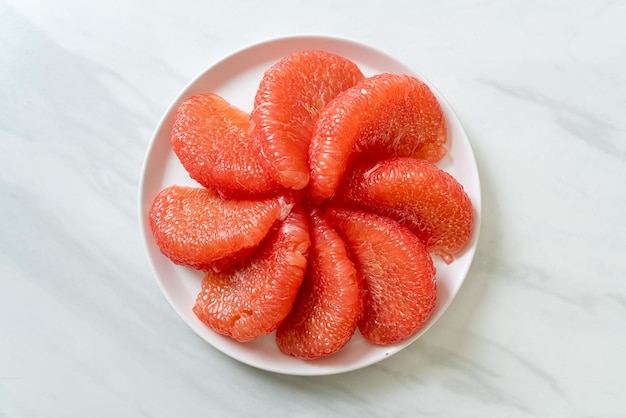 свежие красные фрукты помело или грейпфрут на тарелке
