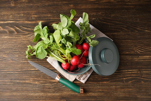 Fresh red radish in bowl on wooden background