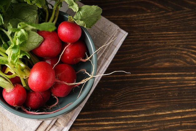 Fresh red radish in bowl on wooden background