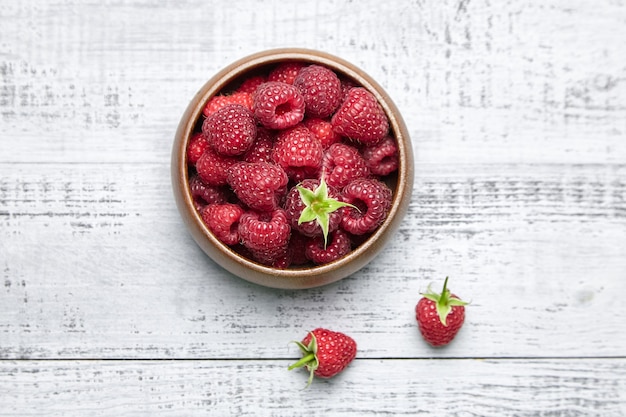 Fresh red raspberries in wooden bowl on gray table top view