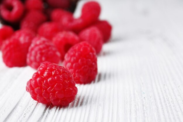 Photo fresh red raspberries on wooden table closeup