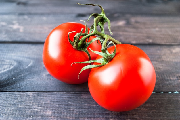 Fresh red ripe tomatoes on a branch on a wooden background