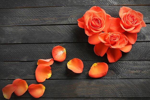 Photo fresh red roses buds in shape of heart on wooden background