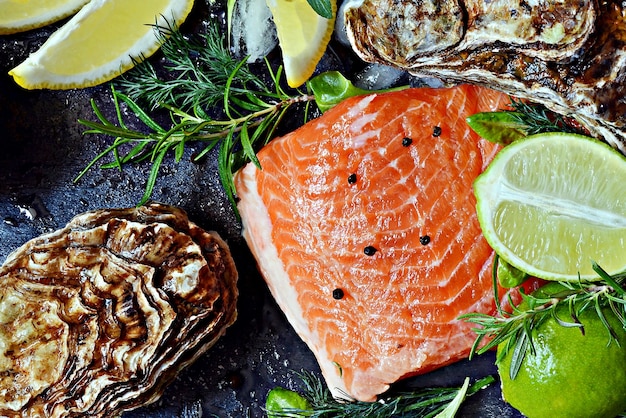 Fresh red salmon trout fish steak with fresh oysters herbs lemon and lime