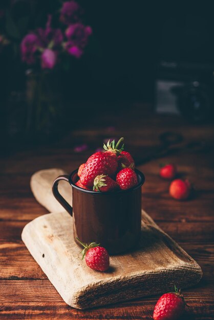 Fresh red strawberries in metal mug on table