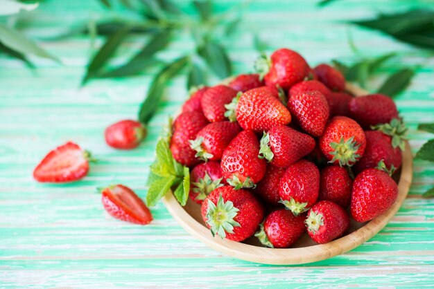 Fresh red strawberries in a plate on a rustic background, seasonal summer berries, selective focus, copy space