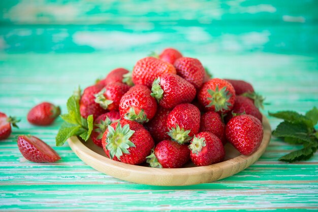 Fresh red strawberries in a plate on a rustic background, seasonal summer berries, selective focus