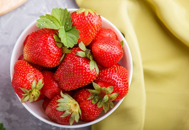 Fresh red strawberry in white bowl. top view.