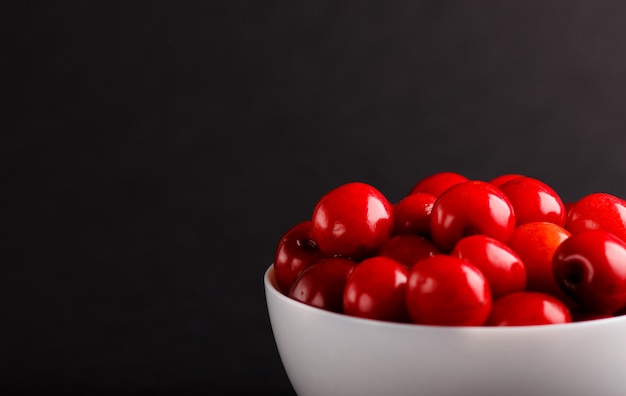 Fresh red sweet cherry in white bowl. side view.