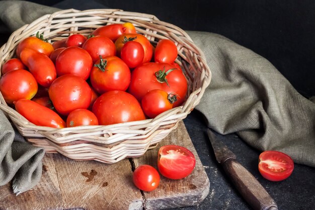 검은 배경에 고리 버들 세공 바구니에 신선한 빨간 토마토