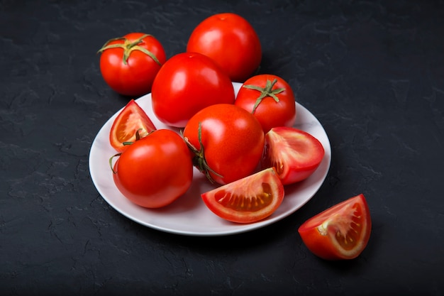 Fresh red tomatoes in a white plate. Close-up, copy space.