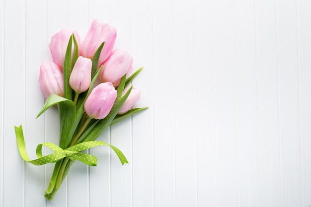 Fresh red tulip flowers bouquet on shelf in front of wooden wall