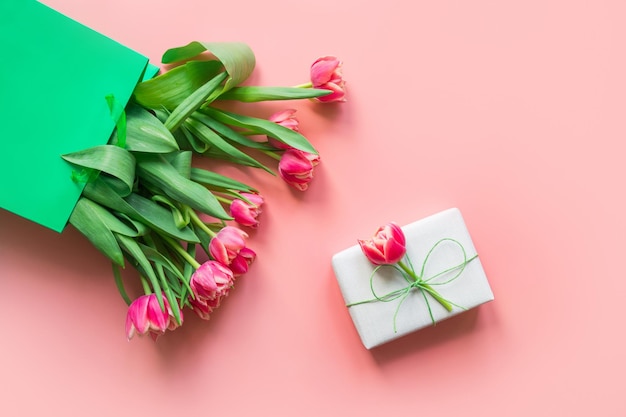 Fresh red tulip flowers in green paper bag on pink Spring Mother day