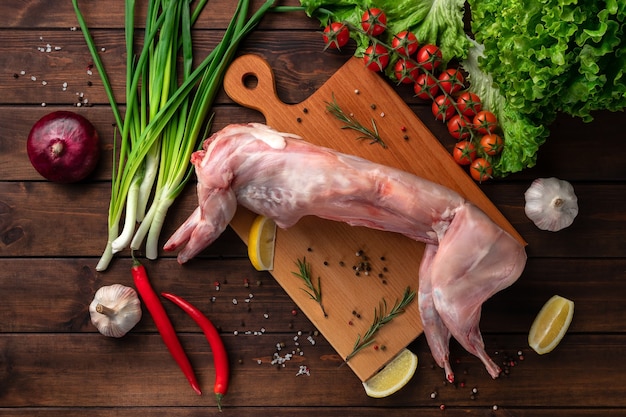 Fresh red whole rabbit meat on a wooden cutting board, top view