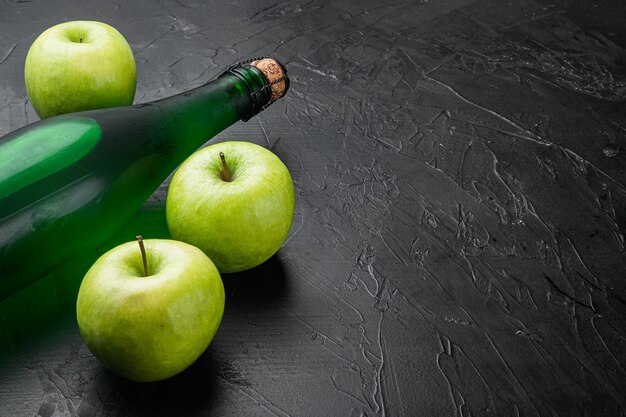 Fresh ripe apples and apple cider vinegar set, on black dark stone table background, with copy space for text