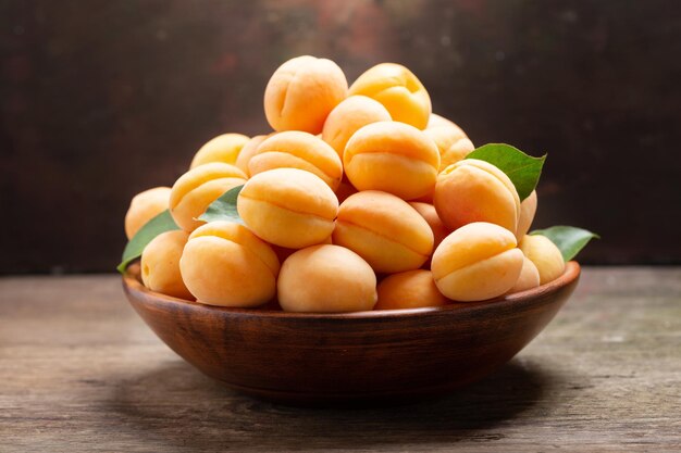 Fresh ripe apricots with leaves in a bowl