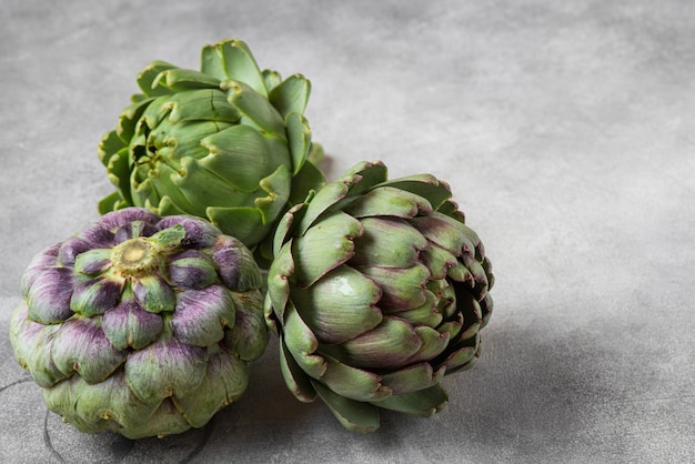 Fresh ripe artichokes flowers vegetable on gray