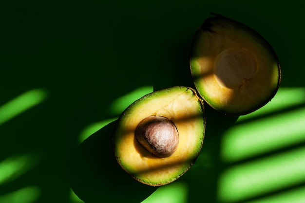 写真 緑の背景に新鮮な熟したアボカドを半分にカット