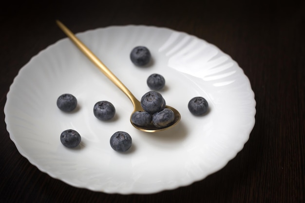 Fresh and ripe blueberries on a spoon, a plate with berries