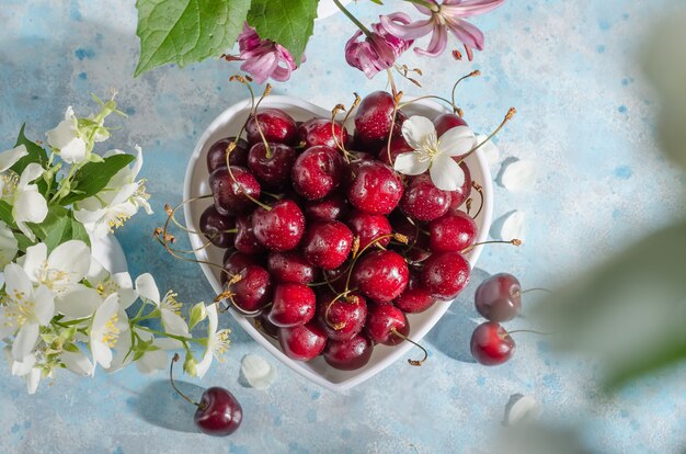 Fresh ripe cherries in a heart-shaped bowl on a blue background