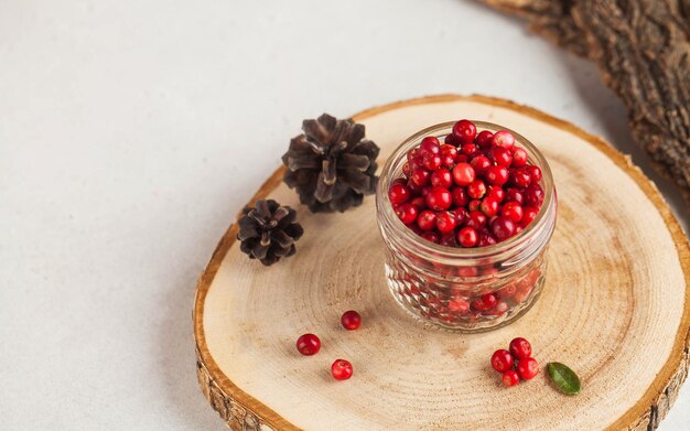 Photo fresh ripe cranberries in a transparent glass jar on a wooden stand autumn useful berries