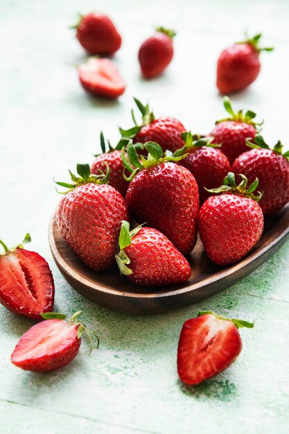 Fresh ripe delicious strawberries in a wooden bowl on a green wooden background